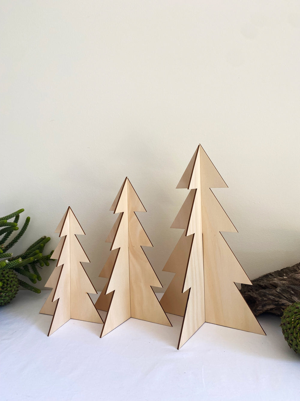 Set of three standing timber Christmas trees made from sustainably sourced hoop pine, featuring a smooth natural wood finish and simple slot-together design, displayed as minimalist festive décor.