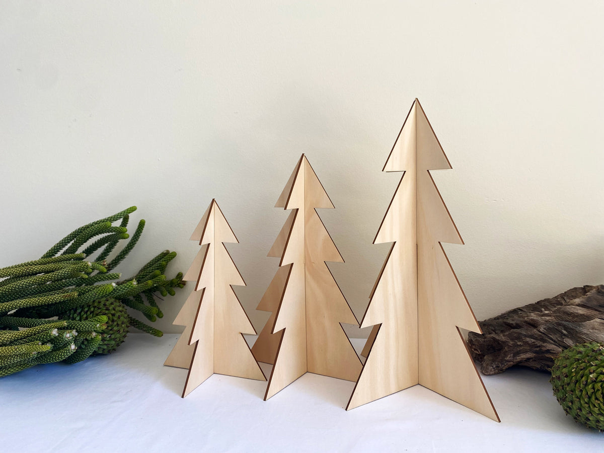 Set of three standing timber Christmas trees made from sustainably sourced hoop pine, featuring a smooth natural wood finish and simple slot-together design, displayed as minimalist festive décor.