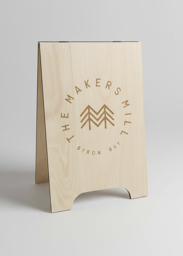 Wooden sign with 'The Makers Mill' logo on a gray background